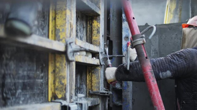 Worker adjusting formwork connection with hammer