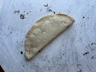 Empanada made with corn masa cooking on a comal in Oaxaca, Mexico