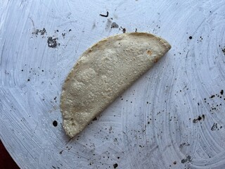 Empanada made with corn masa cooking on a comal in Oaxaca, Mexico