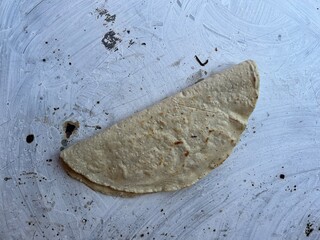 Empanada made with corn masa cooking on a comal in Oaxaca, Mexico