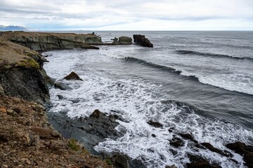 Obraz premium Scenic view of ocean waves crashing against the Vattarnes Sea cliffs during daytime in East Iceland
