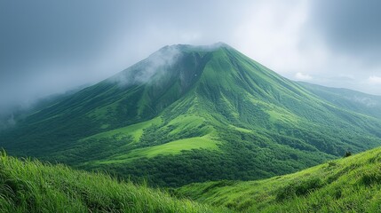 Fototapeta premium A lush, green mountain landscape under a cloudy sky, showcasing nature's beauty.
