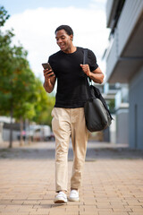 Man walking and using smartphone while carrying a shoulder bag