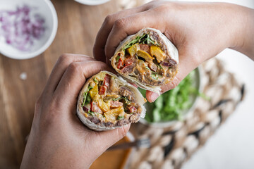 Mexican meat and vegetables burrito in hands