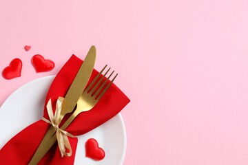Valentine's Day concept. Top view photo with plate, cutlery and confetti on color background with empty space