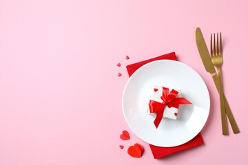 Valentine's Day concept. Top view photo with plate, cutlery, gift box and confetti on color background with empty space