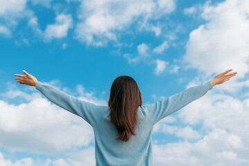 A woman with long hair is standing in the open air, looking up at the sky. The sky is blue with a few clouds, and the woman is enjoying the view
