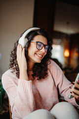 Young caucasian woman enjoying music on wireless headphones at home	