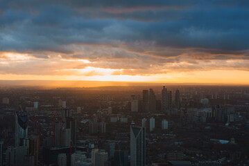 Fototapeta premium View of London's skyline during sunset, featuring prominent skyscrapers and modern buildings under a sky filled with dramatic clouds.