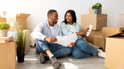 Loving young family thinking about home design, holding apartment plan and working on design for...