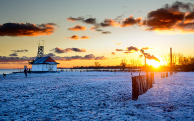 Sunset on Kew Beach in Toronto on a bright snowy winter solstice 2024 empty snow covered beach  ...