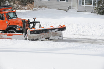 snowplow truck working on removing snow on residential street