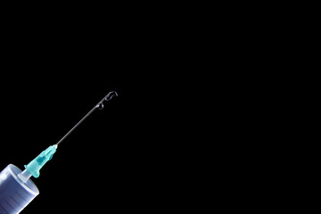 Syringe with a drug injection drop isolated on a black background. Health and medical concept with copy space for text or design, close-up, selective focus