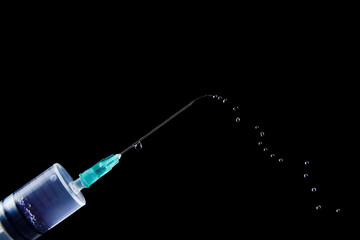 Syringe with injection drops isolated on a black background. Health and medical concept with copy space for text or design, close-up, selective focus
