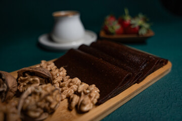 Delicious dessert in a wooden plate with walnuts, strawberries and traditional Turkish coffee on top