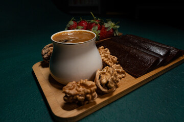 Delicious dessert in a wooden plate with walnuts, strawberries and traditional Turkish coffee on top