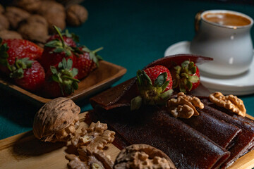 Delicious dessert in a wooden plate with walnuts, strawberries and traditional Turkish coffee on top