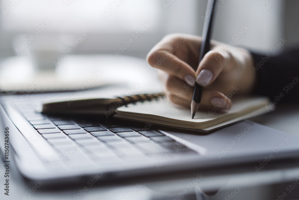 Poster the close-up image showcases a woman's hand inscribing in a notepad on a modern laptop, with a soft-