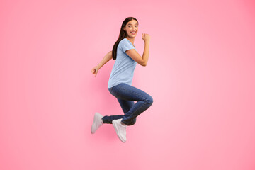 Euphoria Concept. Full length portrait on joyful energetic young woman jumping isolated over yellow studio background. Excited female model celebrating victory, win or triumph, looking at camera