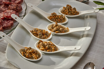 Fresh cockles served in white spoons on a white plate