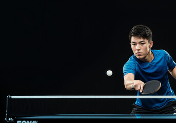 Professional table tennis player hitting the ball with backhand stroke during a table tennis match