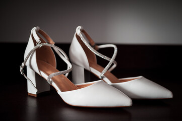 Elegant White Heels with Silver Straps on a Dark Surface