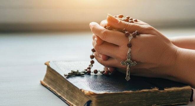 Hands holding rosary over book, suggesting prayer or meditation - Powered by Adobe