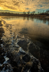 Winter landscape on the pond,frozen pond,blue colors .Landscape with water and ground.Reed on the beach , frozen lake at the morning with sunlights on the sky.Beautiful clouds in the sky,cold and snow