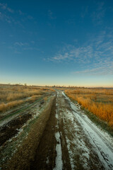 Snowy and frosty field with road,sunrise in the sky.Beautiful clouds in the sky.Nature at the winter time.Winter morning, sunlights over the road , beautiful nature landscape 