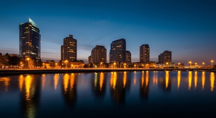 Obraz premium A panoramic view of a city skyline at dusk with glowing lights reflecting on the water