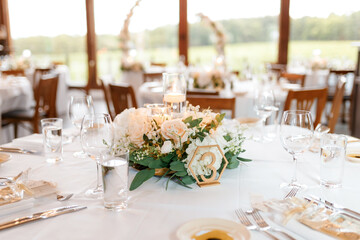 Festive served round table for guests in the restaurant. A wedding table for guests with a white tablecloth is decorated with flowers, served with dishes, waiting for guests, without people