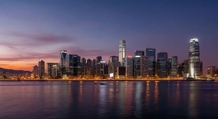 Obraz premium A panoramic view of a city skyline at dusk with glowing lights reflecting on the water