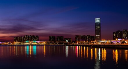 Obraz premium A panoramic view of a city skyline at dusk with glowing lights reflecting on the water