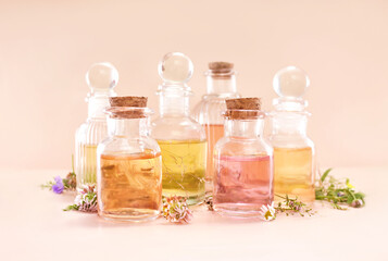 Colorful essential oil bottles and medicinal herbs background, selective focus