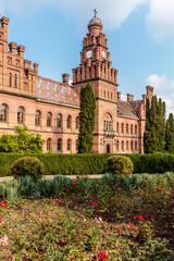 A large brick building with a clock tower and a courtyard with flowers