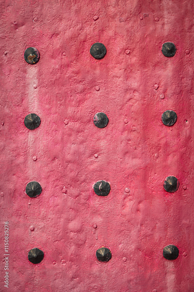 Poster red textured surface with rows of evenly spaced black rivets.