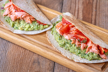Salmon Tacos with Guacamole and Tomatoes on Rustic Table