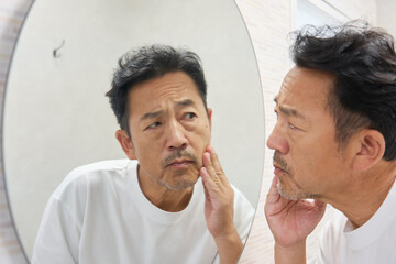 鏡を見て悩む50代男性
