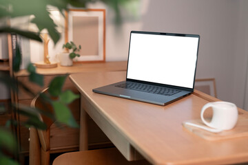 Open laptop with blank screen on a wooden desk in a cozy room home office