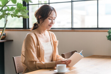 カフェでコーヒーを飲みながら読書をする女性
