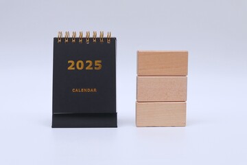 2025 calendar and stack of wooden blocks on white background