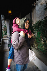 Older sister carrying her tired little girl younger sister on her back.