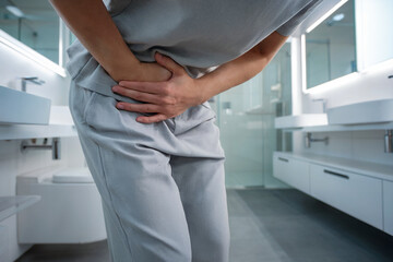 Person Holding Lower Abdomen in Pain in Bathroom