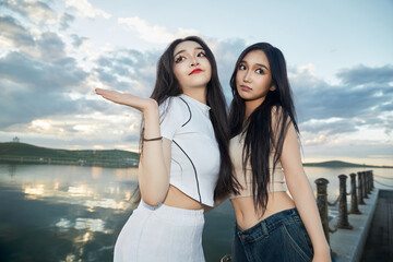 Asian beauties taking photos of the scenery by the lake in the evening