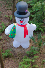 Inflatable snowman dressed for Christmas. Wearing a hat,Red and black clothes. Green grass, brown...
