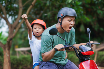 A joyful asian father and son ride a electric scooter, sharing excitement and adventure together.
