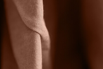 Close up of brown fabric with detailed texture and soft folds in subtle light.