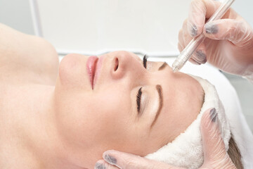 Caucasian female adult receiving eyebrow microblading treatment in beauty salon.