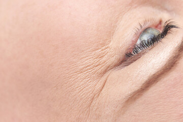 Close up of caucasian female mature eye with detailed wrinkles and expression lines.