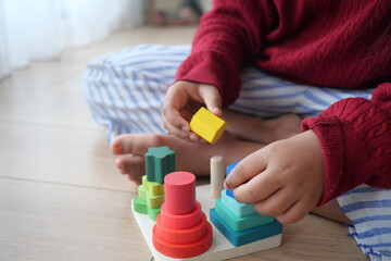 A Child Enjoys Playing with Vibrant and Colorful Stacking Toys on a Wooden Floor